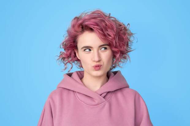 Person with pink hair looking thoughtful. 