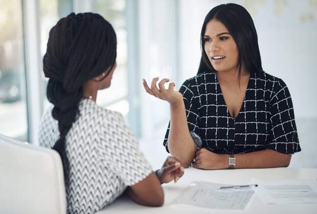 Two people talking at a table in an office meeting room.