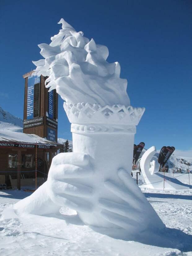 Снежная скульптура, изображающая руки, которые держат Олимпийский огонь.