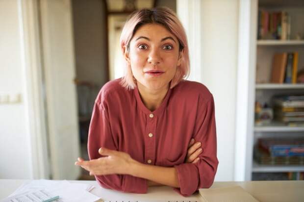 Someone in a reddish shirt is seated and looking toward the camera with an amazed expression.