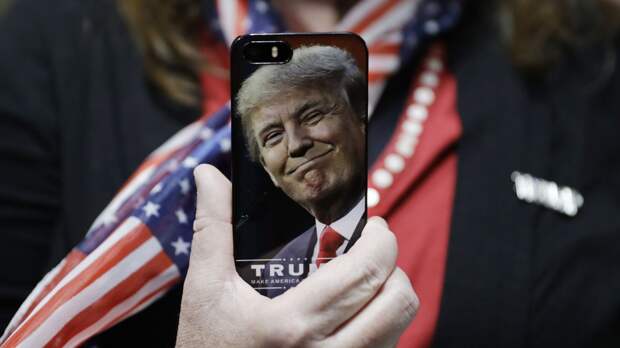 Женщина держит телефон с фотографией Дональда Трампа во время предвыборной кампании в США - ИноСМИ, 1920, 23.11.2019