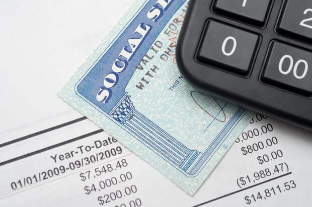 A calculator on top of a Social Security card on top of a financial statement.