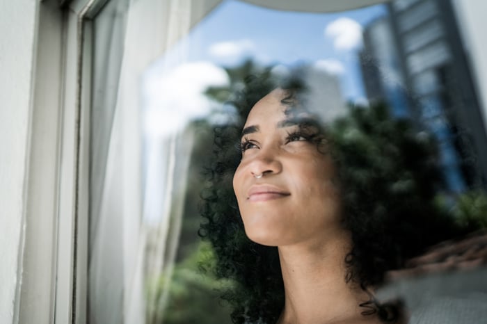A person looking out a window, smiling.