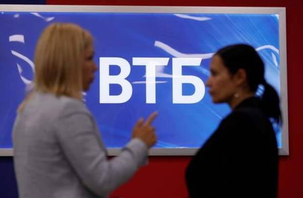 Employees pose for a picture near a board showing the logo of VTB during a tour at a branch of VTB bank in Moscow, Russia May 30, 2019. REUTERS/Evgenia Novozhenina