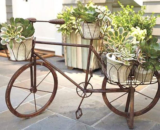 Старыми велосипедами стало популярным украшать садовые участки, ведь они очень подходят на роль подставки для горшков, кадок и вазонов