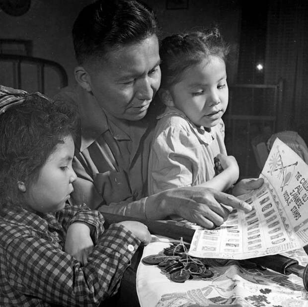 Мужчина Навахо, ветеран Второй мировой войны показывает детям свою коллекцию японских марок и монет. 1948 индейцы, история, навахо, фотография