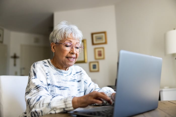 Someone sitting at a table typing on a laptop.