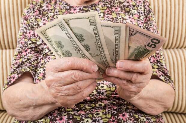 A seated person counting an assortment of cash bills in their hands.