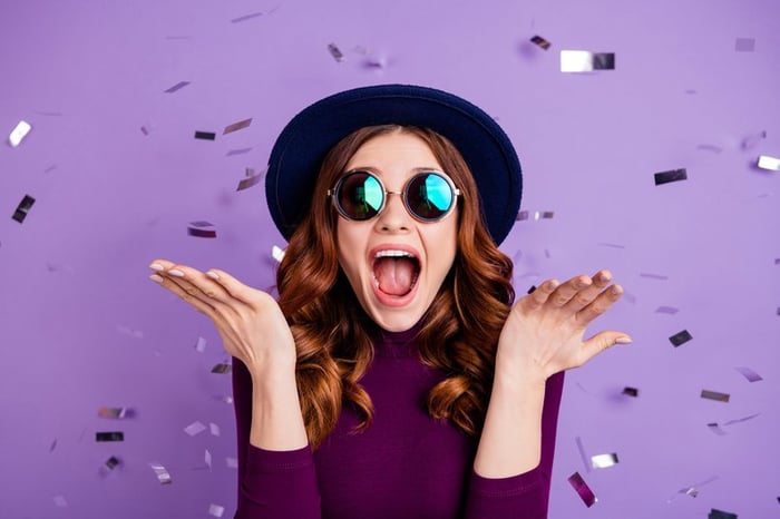 A stylish young woman celebrating and throwing confetti in the air.