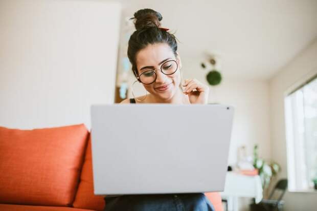 Smiling person looking at laptop.