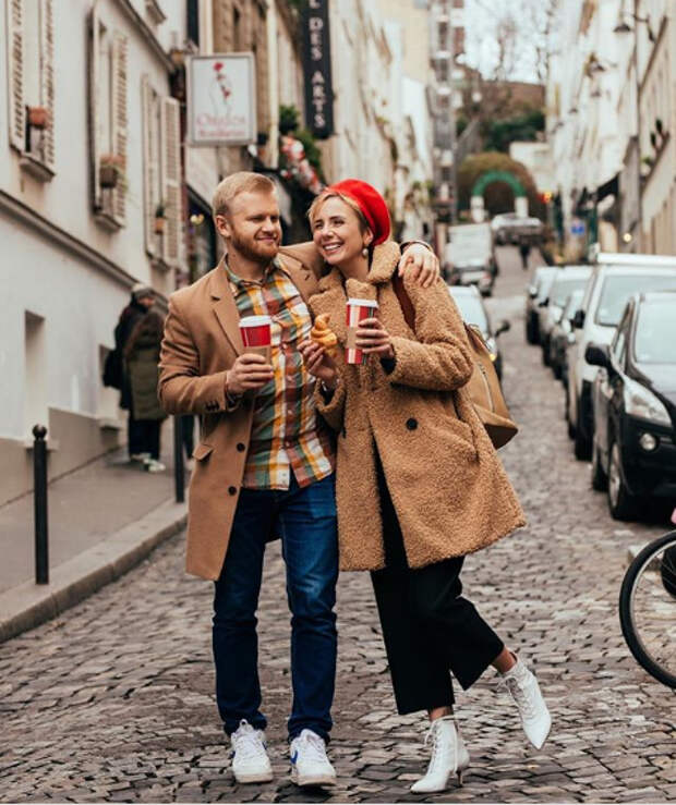 пара стоит в обнимку на улице со стаканами кофе в руках