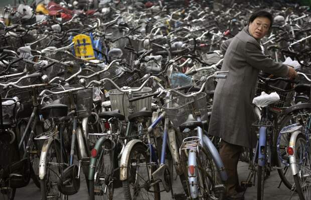 Женщине как-то удалось припарковать свой велосипед на велостоянке в Пекине, и теперь она пытается выбраться из этого моря колес и рулей. китай, люди, население