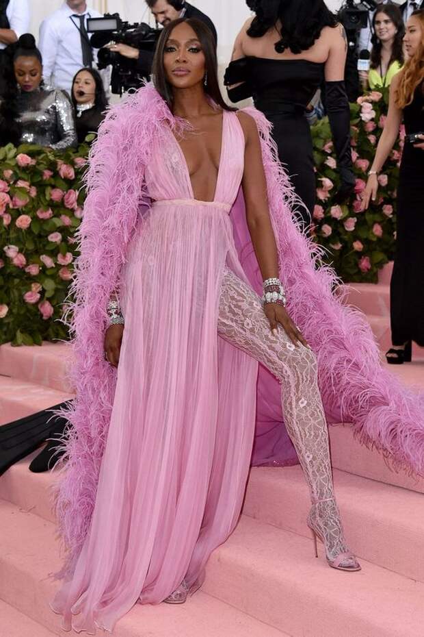 Naomi Campbell in Valentino Haute CoutureNaomi Campbell rocked a candy pink silk chiffon Valentino Haute Couture dress, paired with a cape embellished with feathers and sequins, designed for her by creative director Pierpaolo Piccioli. The supermodel finished her look with stacked bracelets, strappy sandals and lace tights.