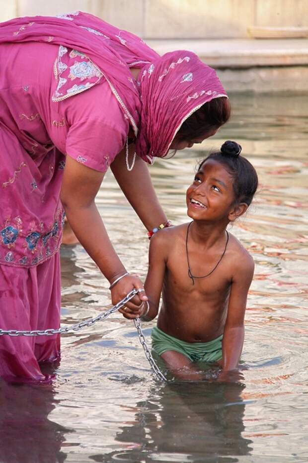 Мама купает сына в святых водах в Золотом храме Амритсара.