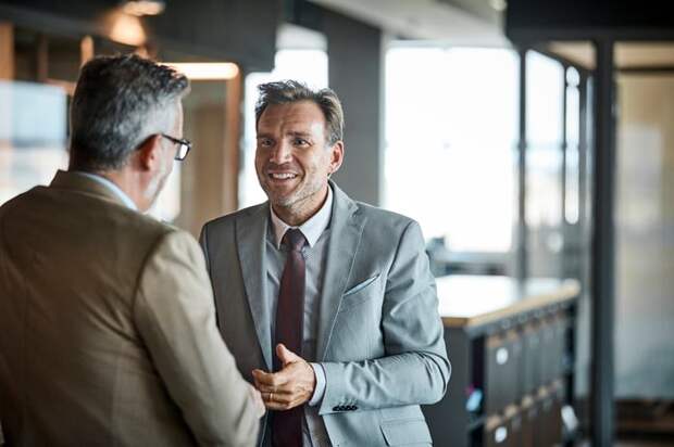 Two people in business attire standing and talking.