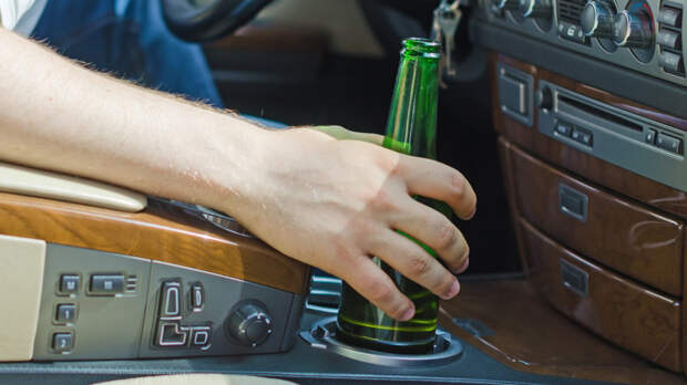 Driving Under the Influence. Male hand with bottle of beer.