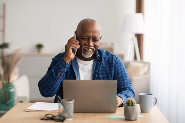 Person talking on the phone and using a laptop.