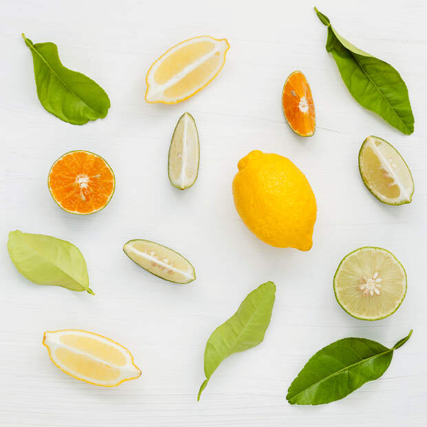Mixed fresh citrus fruits and leaves background. Fresh lemons, lemon slice ,lime and orange on white wooden table with flat lay.