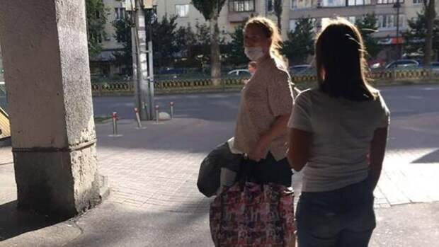 Женщина несет своего ребенка в пакете