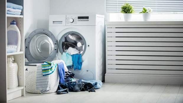 Pile of laundry in front of a washing machine