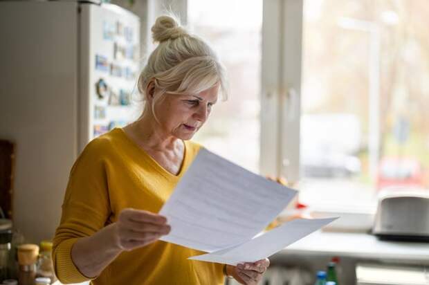 Person studying documents in their kitchen.
