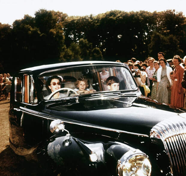 Королева Елизавета Вторая отвозит своих детей, принца Чарльза и принцессу Анну, в Виндзор в окружении зрителей.