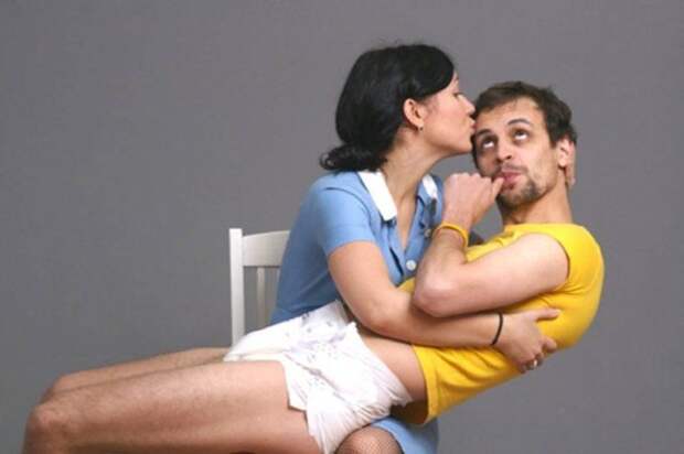 женщина целует мужчину у нее на коленях