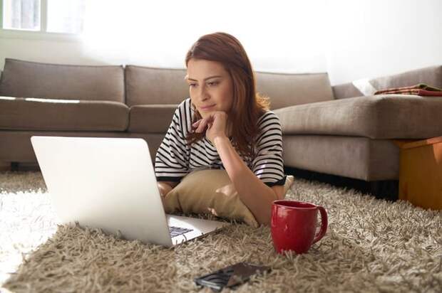 Woman using her laptop on her living room floor