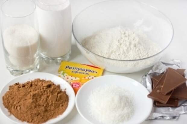 Для приготовления шоколадно-кокосового кекса нам понадобится кокосовое молоко, сахар, какао порошок, пшеничная мука, разрыхлитель, кокосовая стружка, молочный шоколад, масло подсолнечное рафинированное.