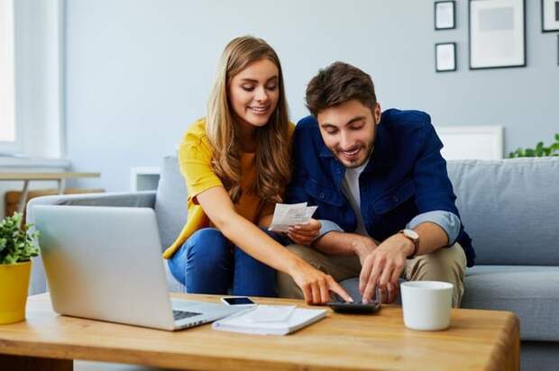 A happy couple with a calculator and bills.
