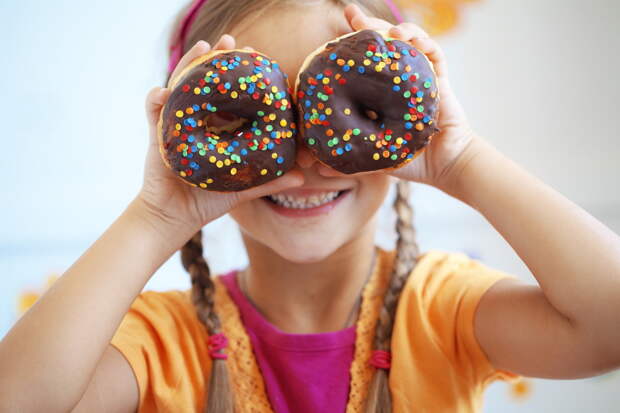 Cute kid girl eating sweet donuts