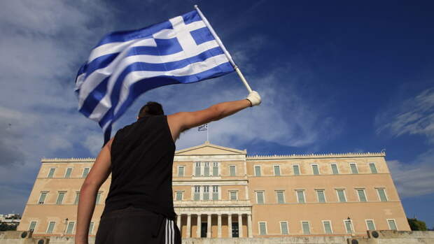 A protester raises Greek flag in front of the parliament during a rally against a new austerity package at Athens' Syntagma square