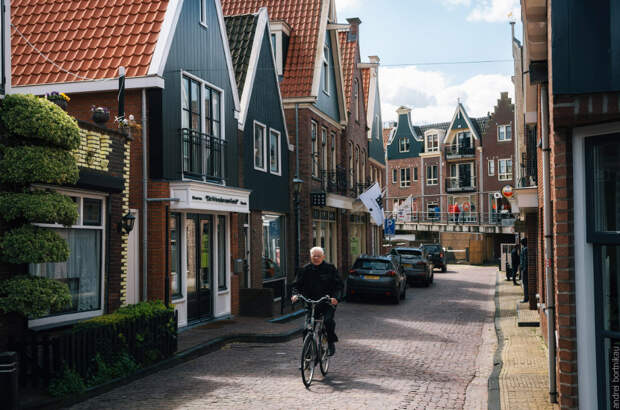 Resident of the village of Volendam by bike in front of the typical traditional houses, Netherlands.