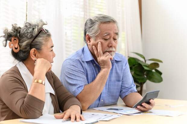A visibly concerned couple using a calculator to analyze their financial situation. 