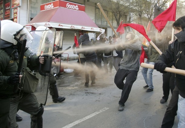 A policeman sprays tear gas at protesters during riots in Thessaloniki