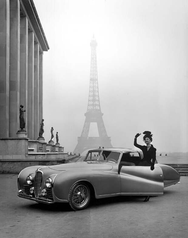 Модель в одежде от модельера Жака Фата позирует рядом с автомобилем «Делайе» 1947 года на фоне Эйфелевой башни. 1947 год