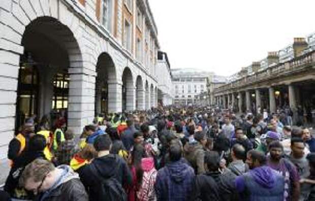 People queue outside an Apple shop in London, Friday, …