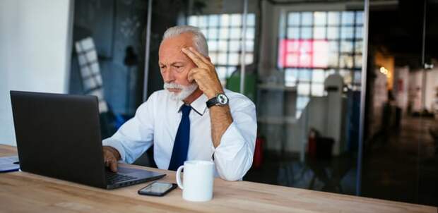 A person with a serious expression looking at a laptop.