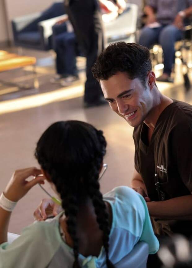 Frost smiling at a patient who is using his stethoscope on Chicago Med S10 E1