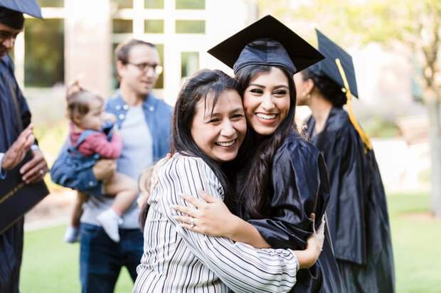 A person hugging another person in a cap and gown.