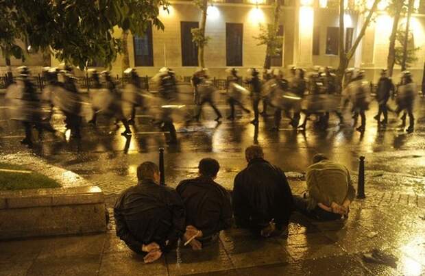 Detained protesters sit on the street as riot police leave after clashes in Tbilisi