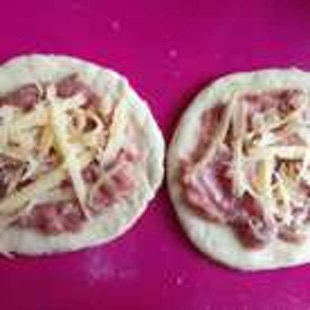 Половину теста раскатать, выдавить стаканом кружки (обрезки собрать и потом снова раскатать, чтобы из них тоже вырезать кружки), на каждый выложить 1 чайную ложку начинки и сверху притрусить тертым сыром.