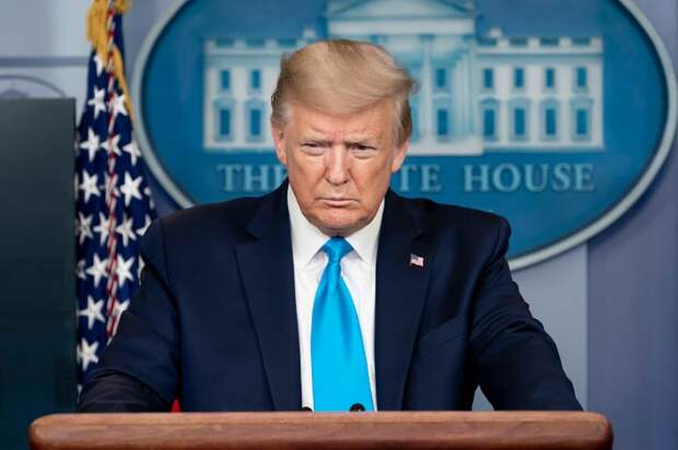 Donald Trump speaking with reporters from behind the presidential podium.