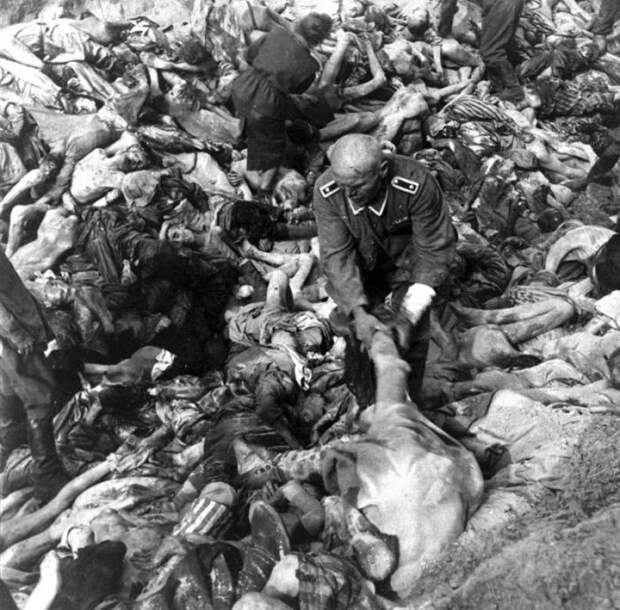 Немецкий солдат СС среди сотен трупов во время массового захоронении в Бельзене. 