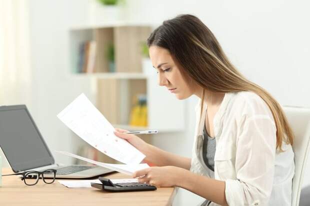 Woman typing on a calculator while looking at a document