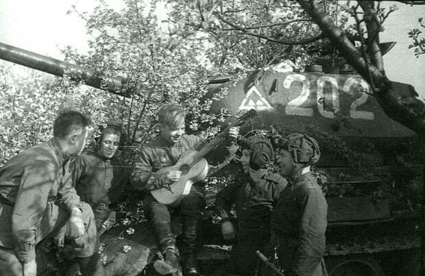 29. Советские танкисты у танка Т-34-85 в Берлине 9-го мая 1945 года слушают товарища, играющего на гитаре. Великая Отечественная война, берлин, война, история, фотографии