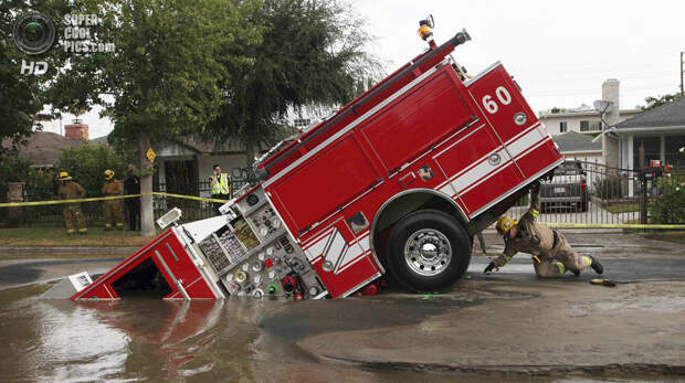 США. Лос-Анджелес, Калифорния. 8 сентября 2009 года. Пожарный автомобиль, попавший в карстовую воронку посреди дороги. (AP Photo/Nick Ut)