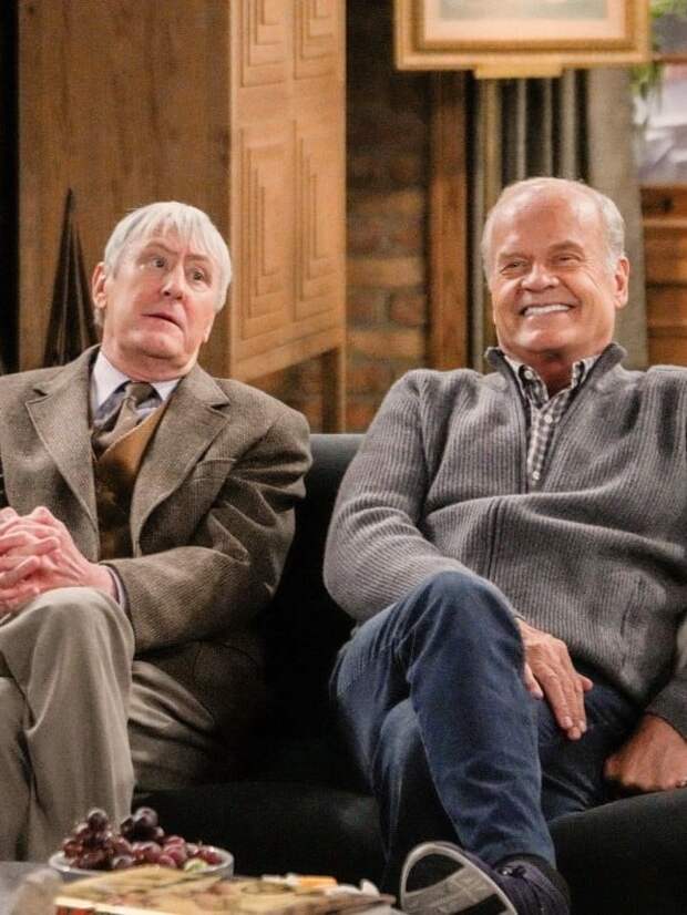 Frasier and Alan sit next to each other on a couch
