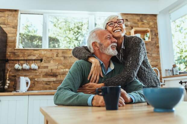 Smiling, embracing couple standing in kitchen.
