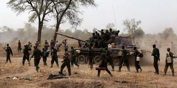 South Sudanese soldiers walk alongside a tank as they withdraw from the town of Jau